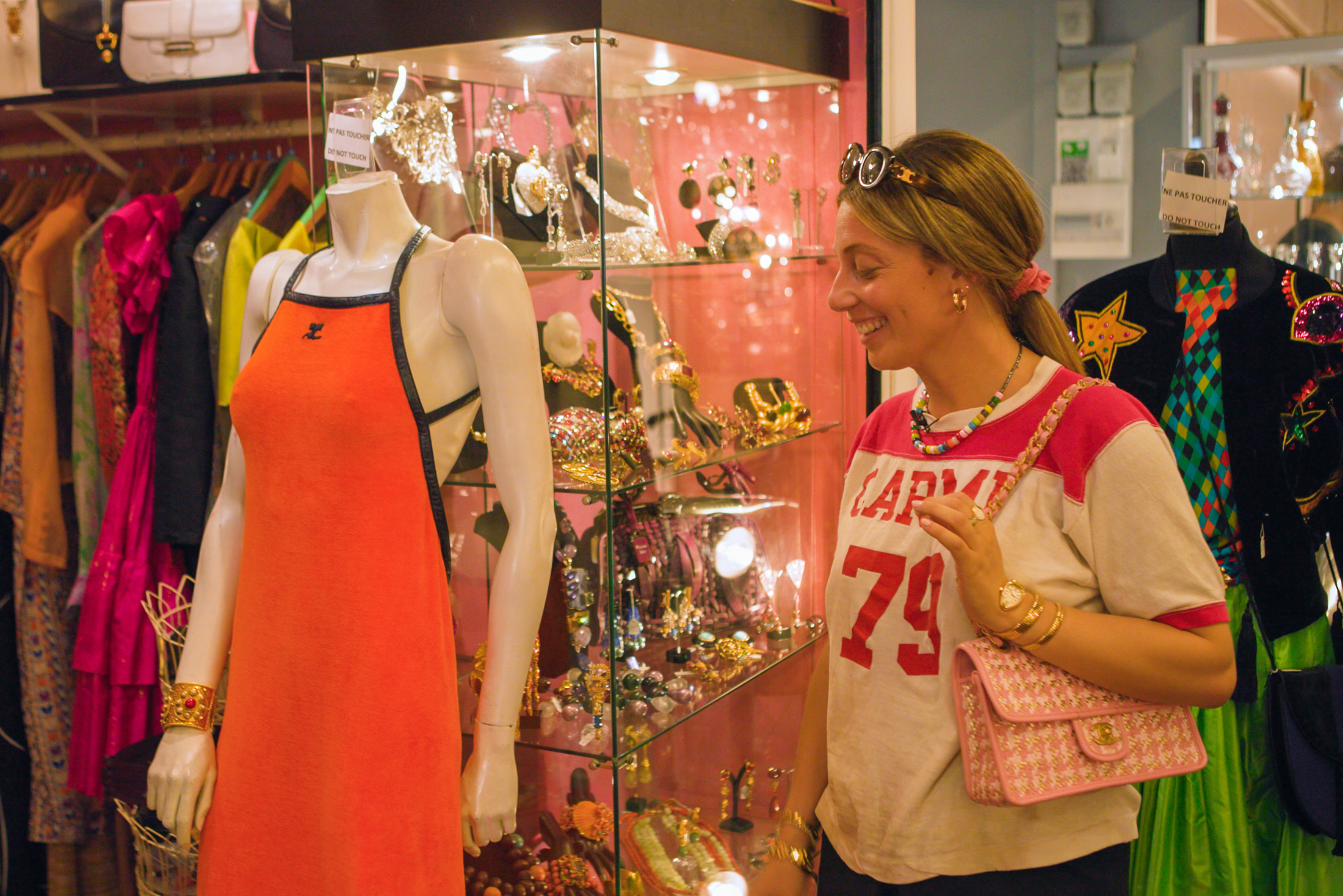 Malaika smiles while observing an orange dress on display at a boutique