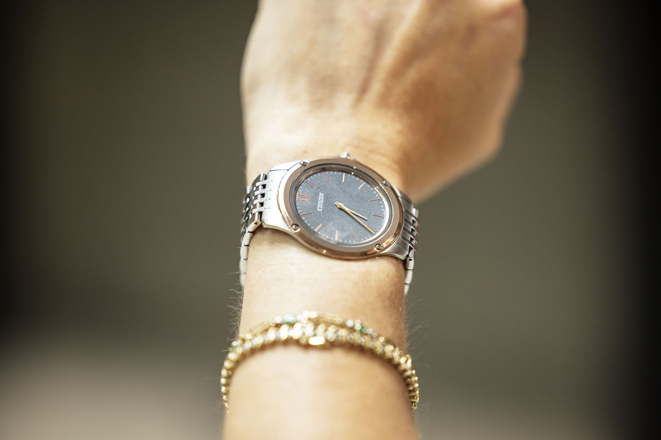 A woman's wrist, wearing a thin CITIZEN watch