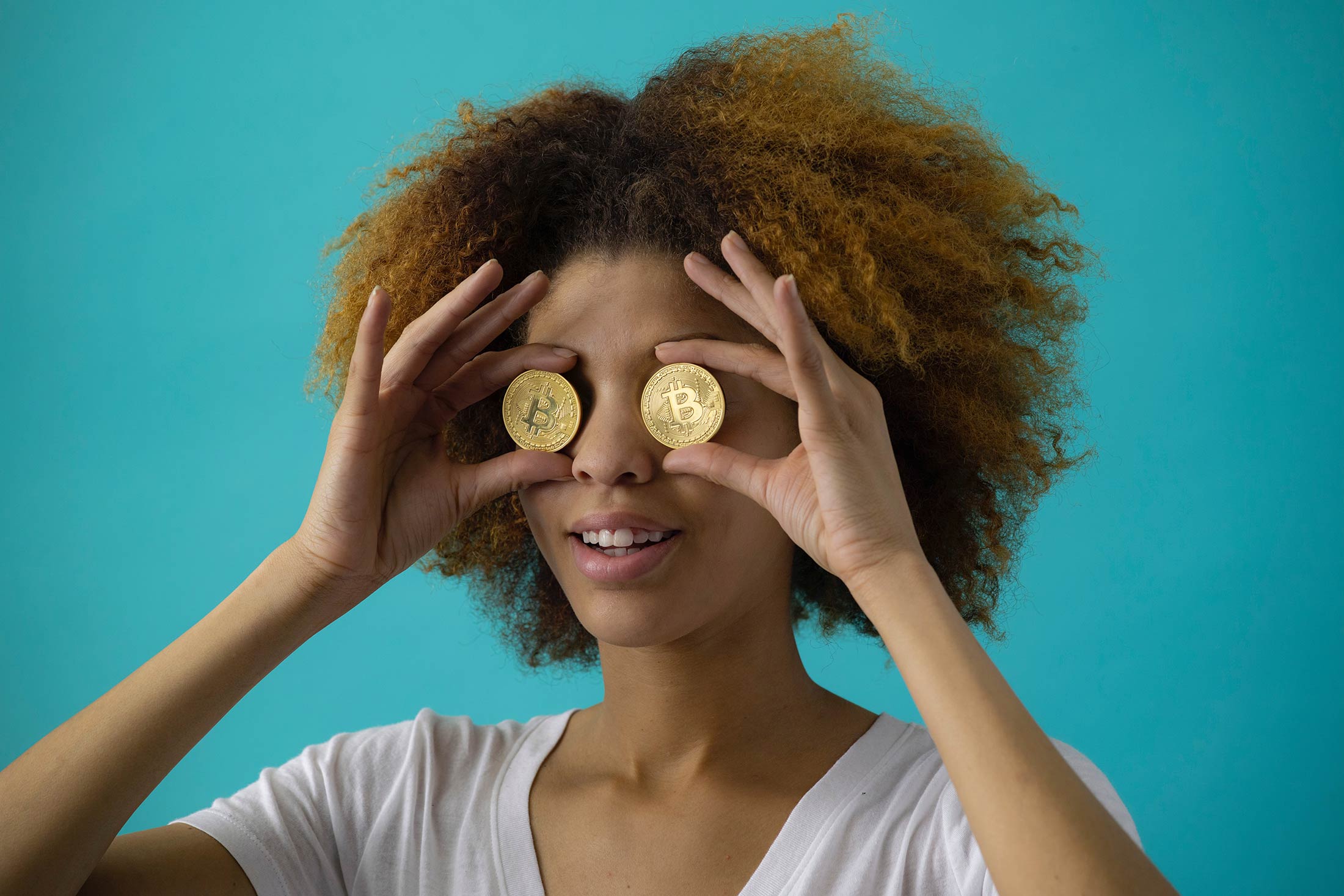 Model holding gold coins up to her eyes.