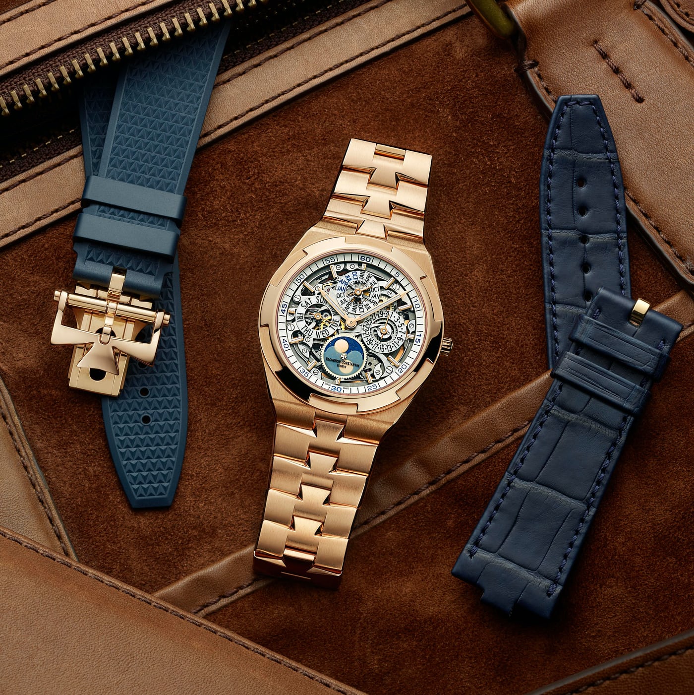 A pink gold Vacheron Constantin watch with two straps next to it on a leather background