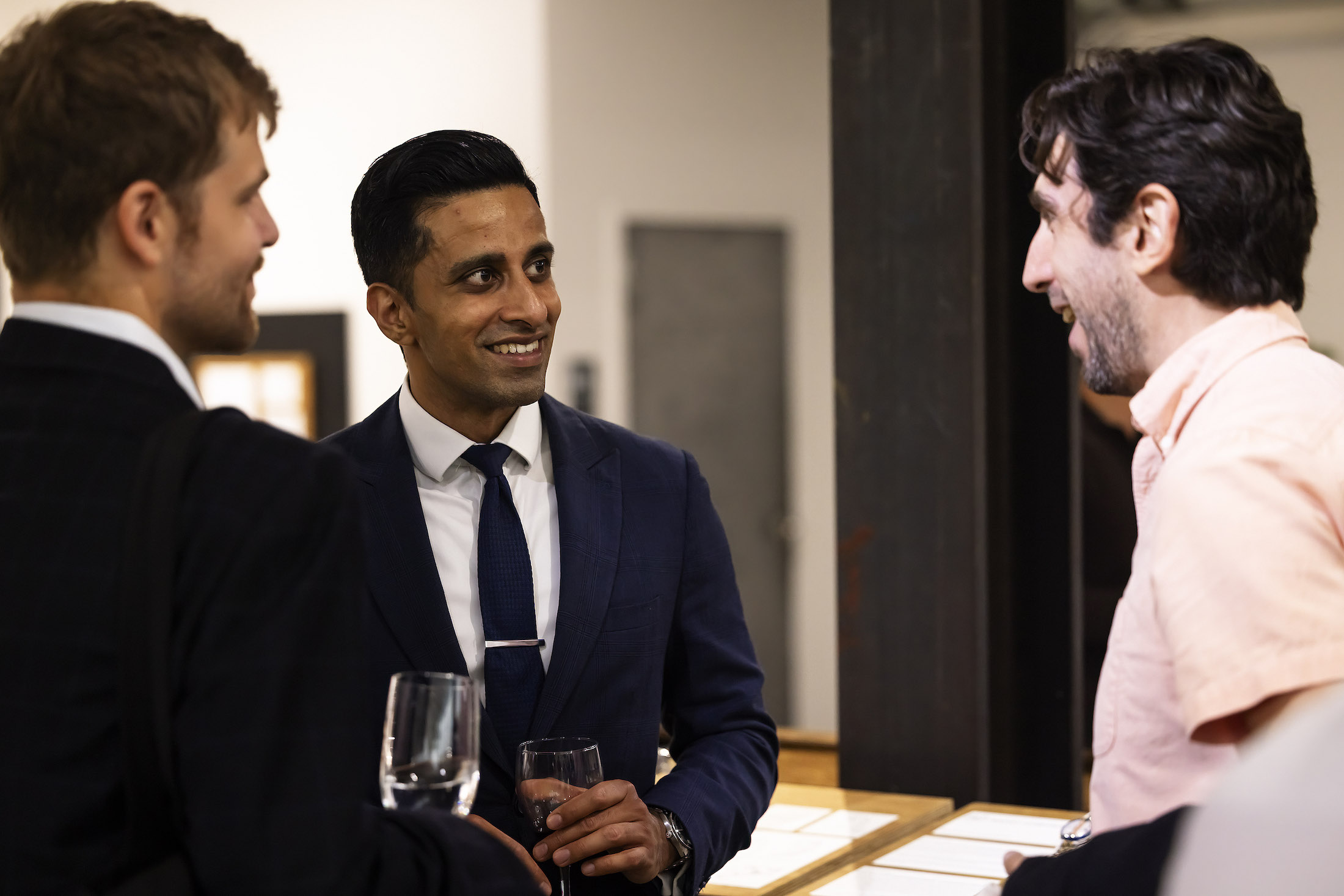 Three men standing with drinks in their hands