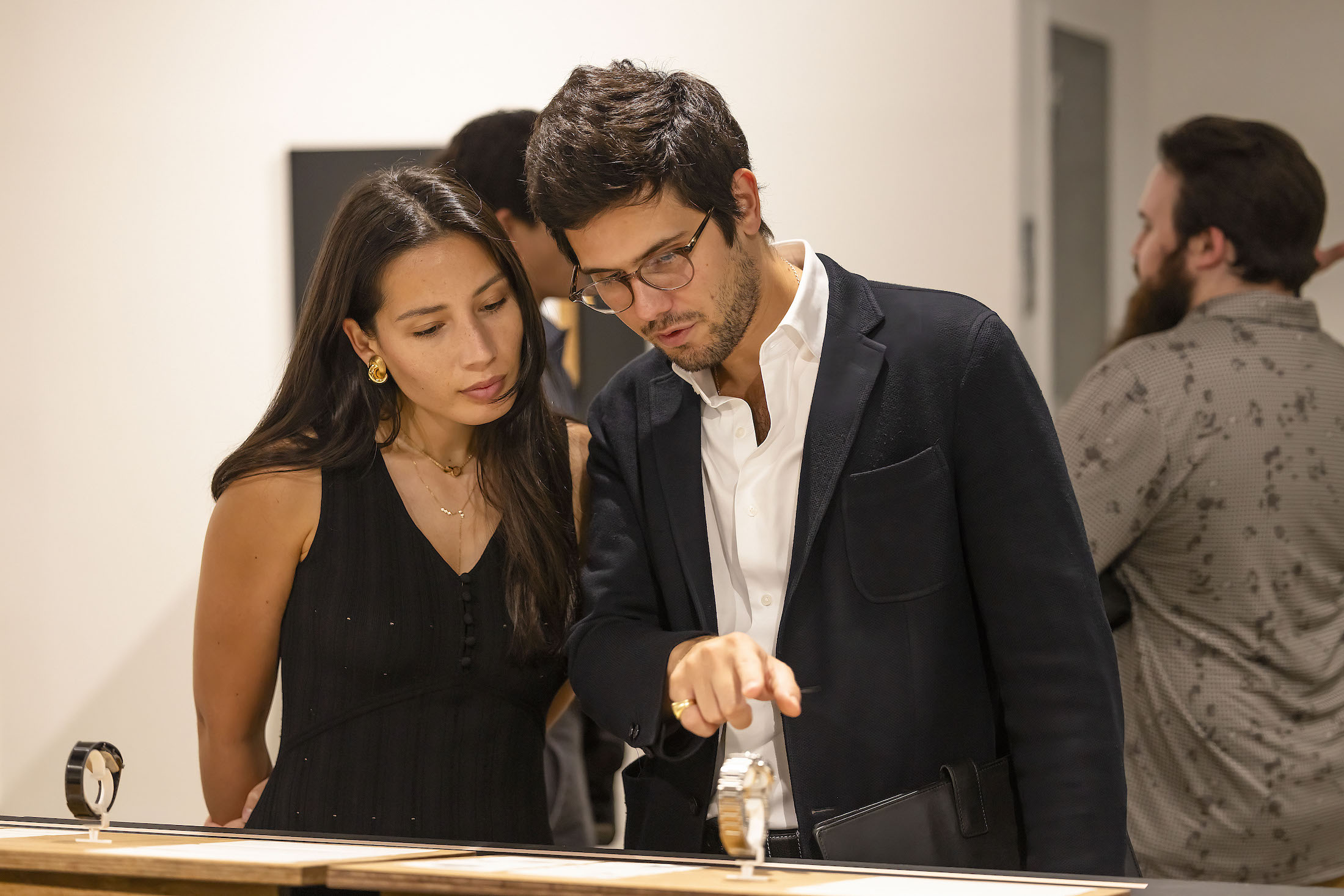 A woman and man pointing at a watch