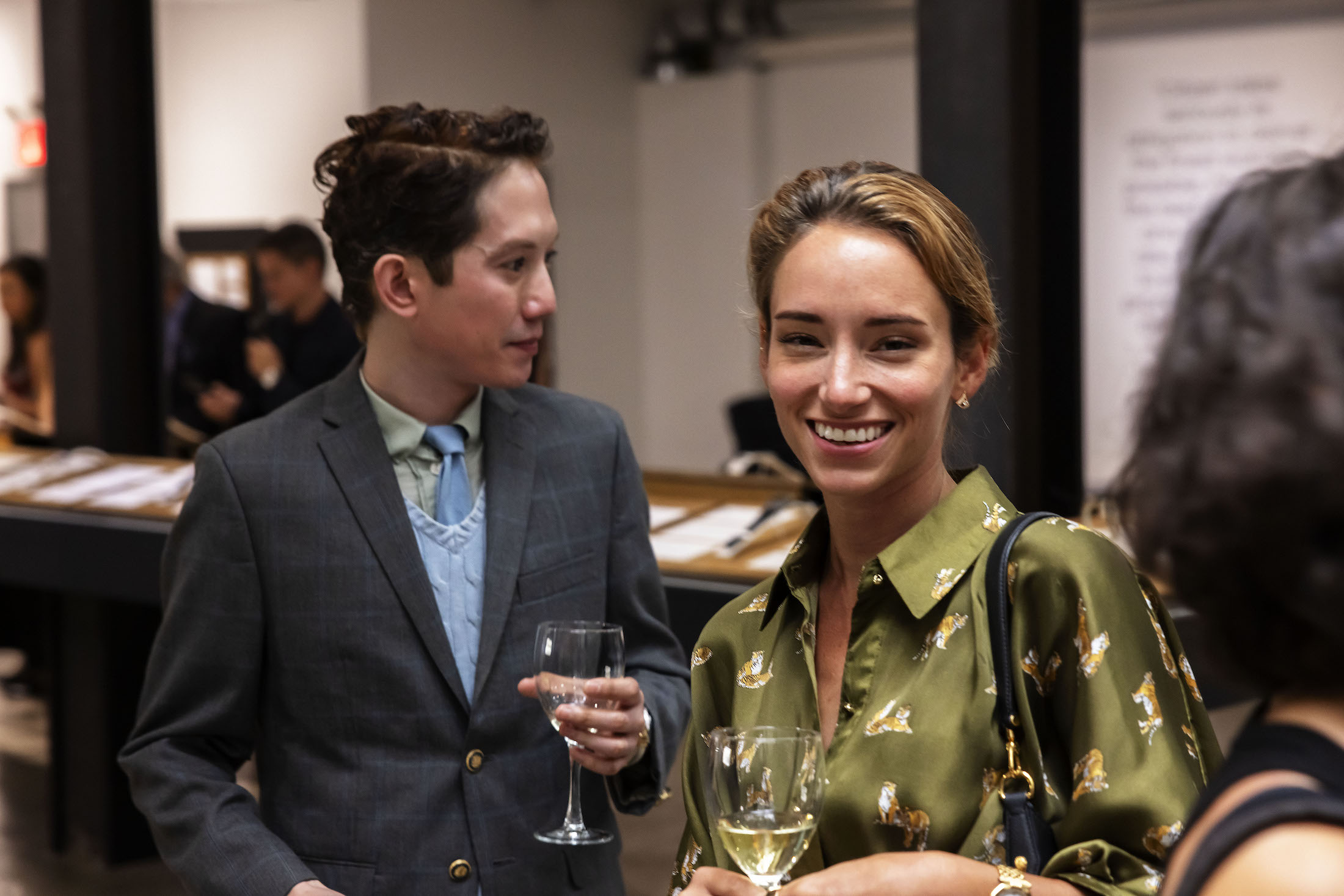 Two people smiling with drinks in their hands.