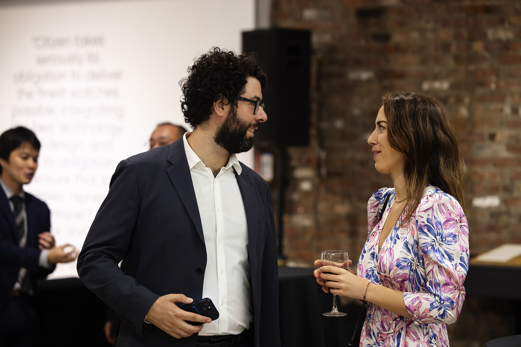 A man with curly hair and a woman talking