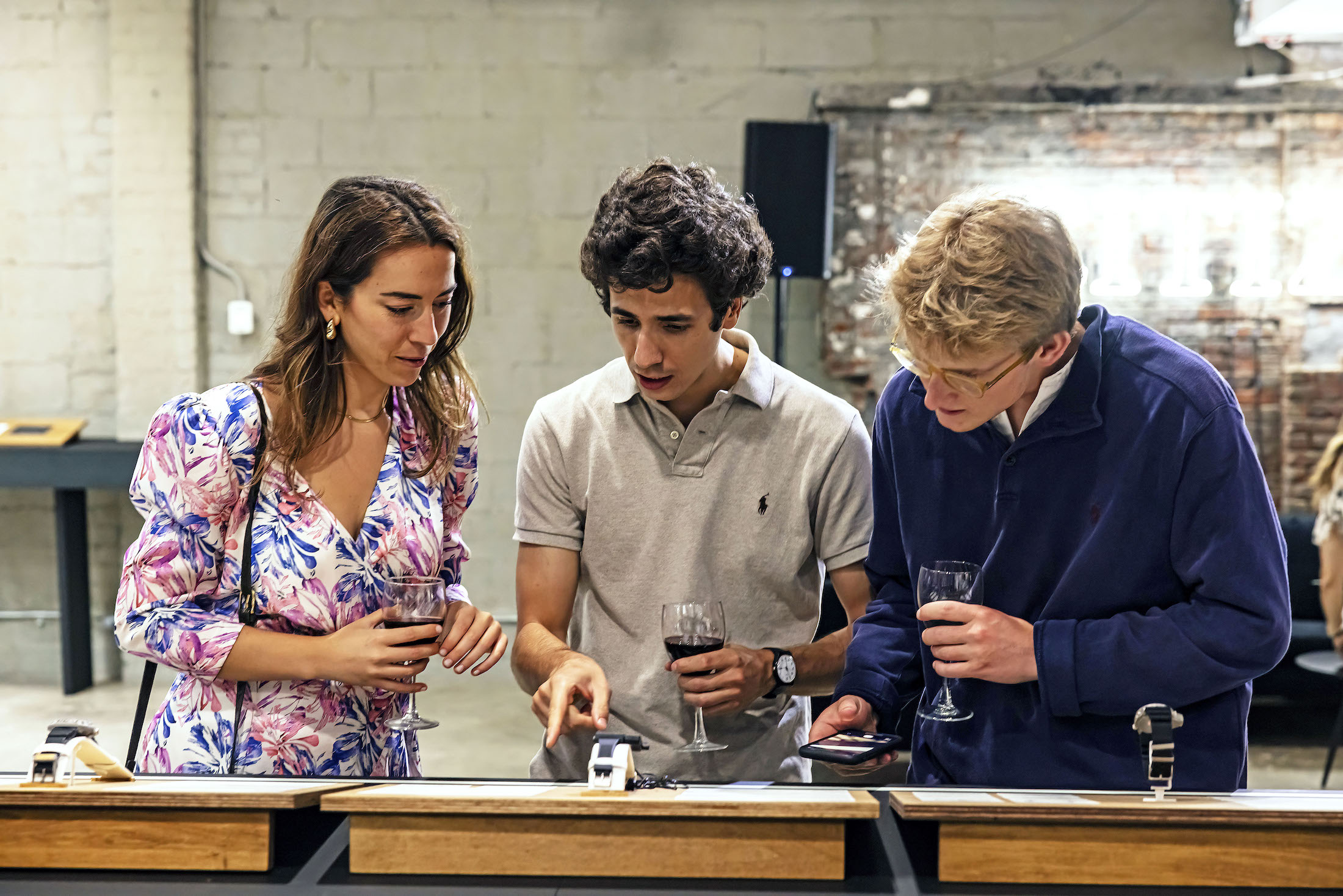 A woman and two men looking at watches