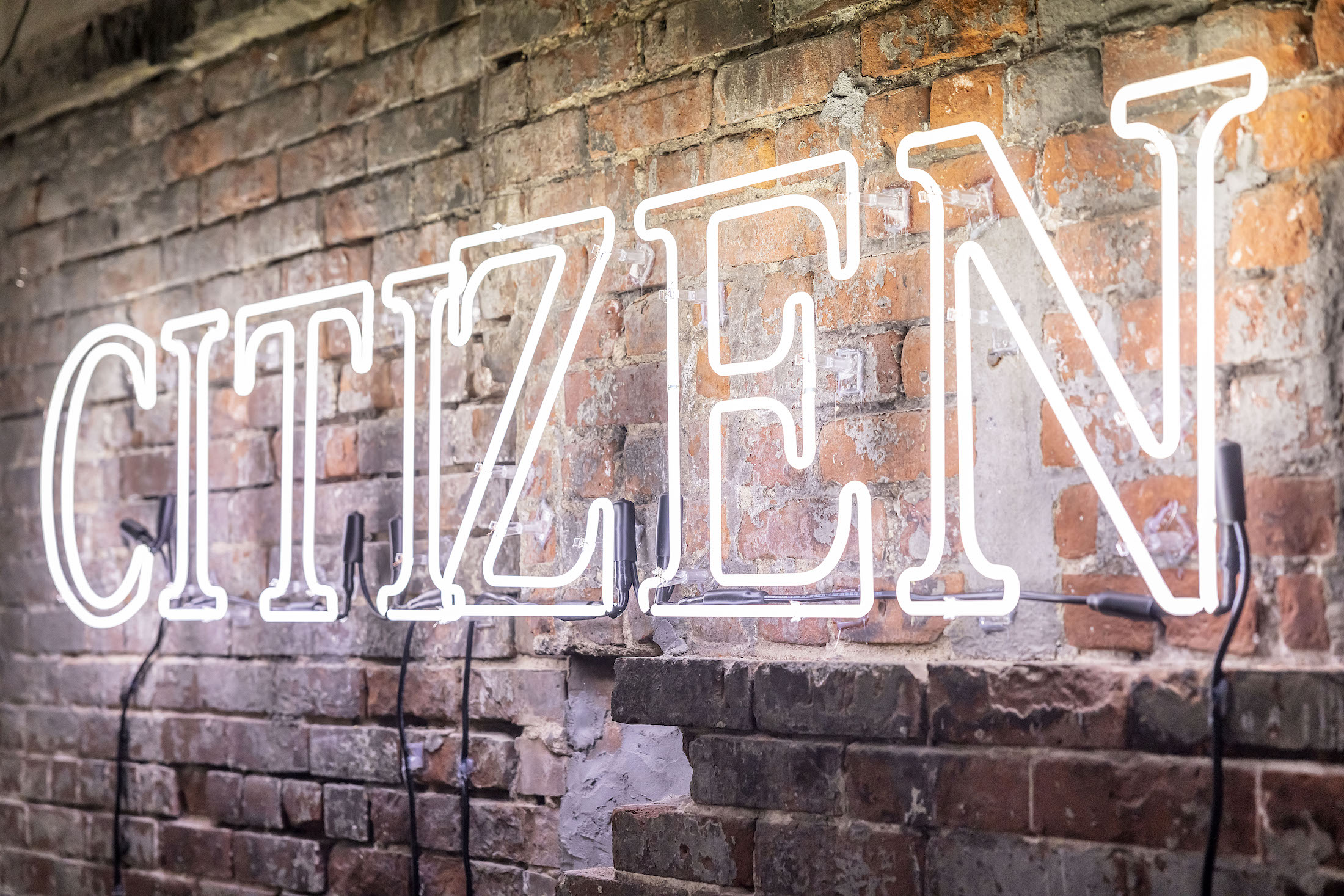 A neon white sign that reads CITIZEN